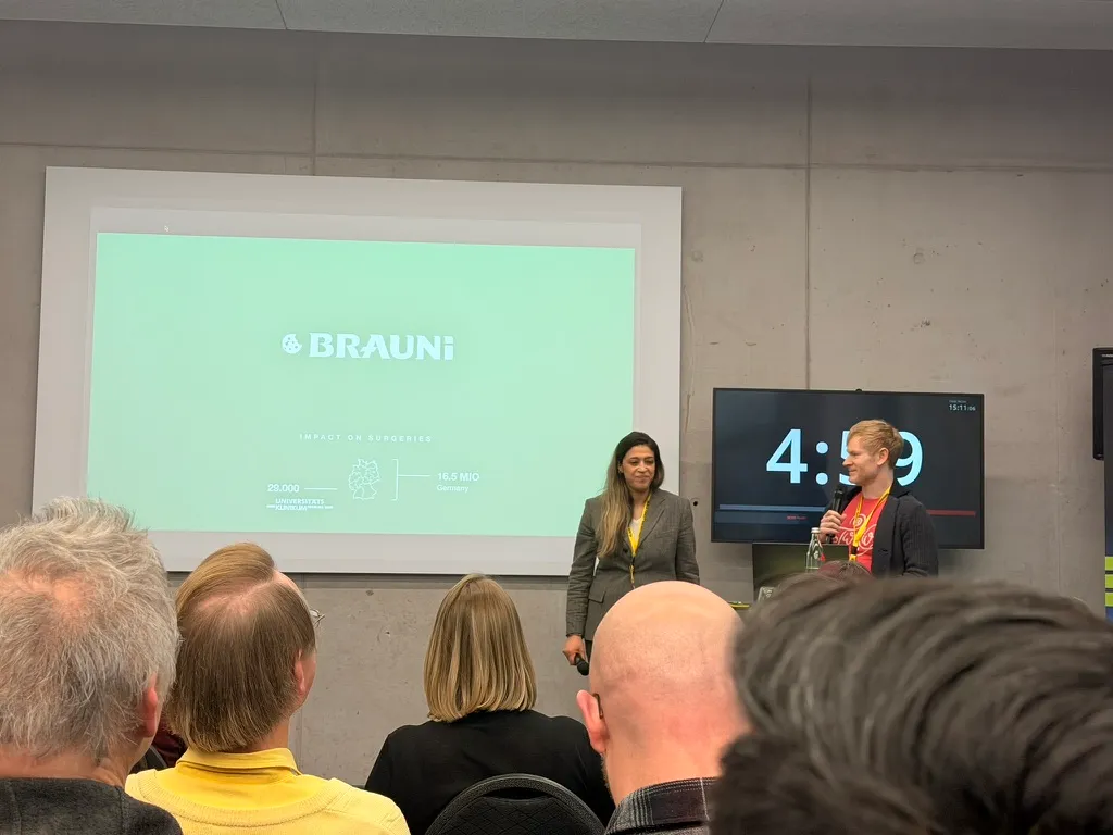 Two team members pitching BRAUNi to the audience, with the countdown next to them